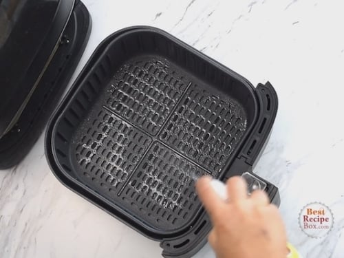 Spraying air fryer with oil