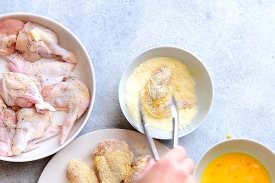Dipping the chicken wing in grated parmesan