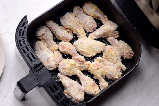 Uncooked parmesan wings in air fryer basket