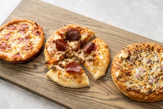 3 personal pizzas on a cutting board