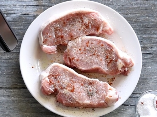 Uncooked pork chop on a plate and seasoned