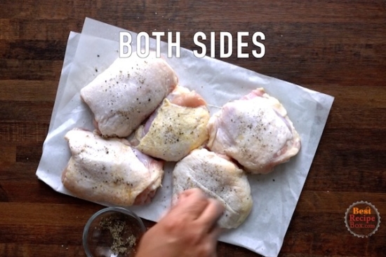 Seasoning raw chicken thighs with salt and pepper