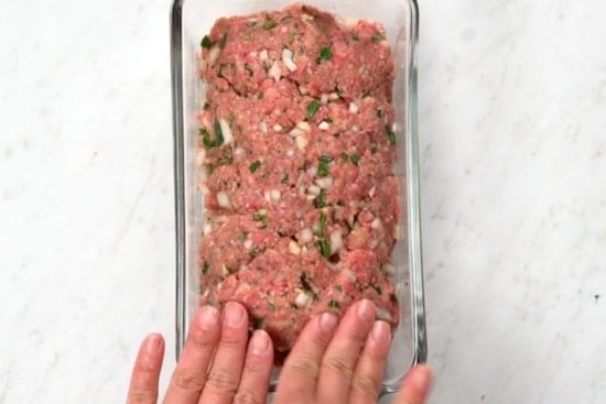 Pressing meatloaf mixture into a loaf pan