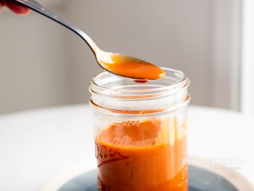 spooning buffalo wing sauce above jar