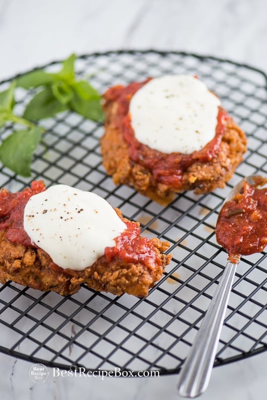 Crispy Chicken Parmesan Sandwich with Best Parmesan Chicken Recipe on a cooling rack with spoon 