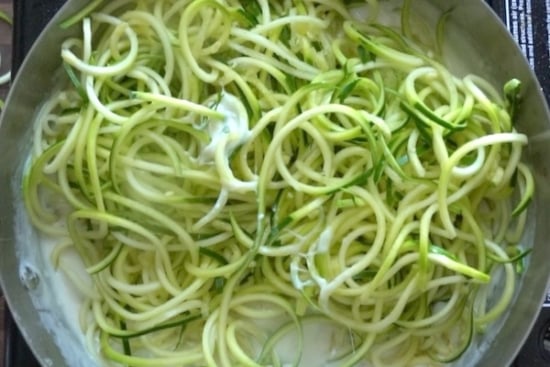 Zoodles being stirred into sauce