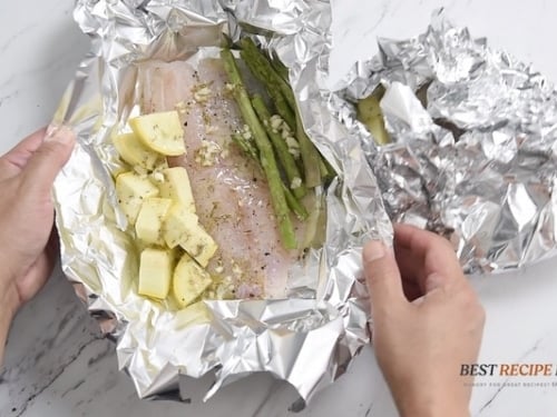 Folding the foil over the fish fillet with the veggies and garlic butter mixture