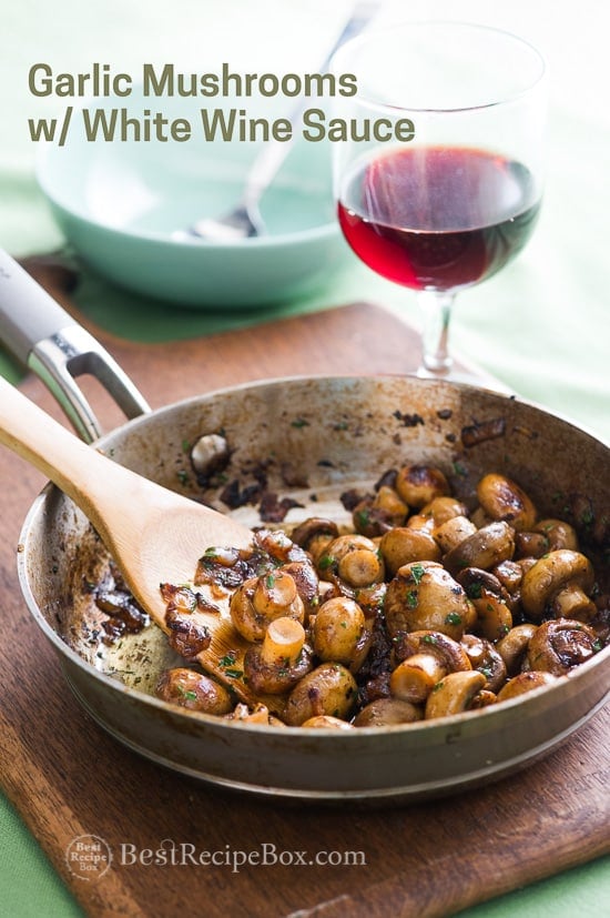 Sautéed Garlic Mushrooms with White Wine Sauce in a cooking pan with a wooden spatula