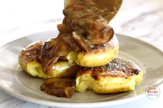 Pouring gravy over crisped potatoes on a plate