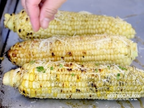 Sprinkling parmesan on corn