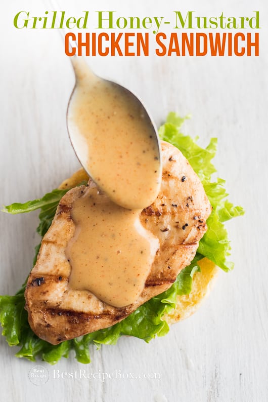 Grilled Honey Mustard Chicken Sandwich with Easy Honey Mustard Sauce Recipe on a cutting board with spoon