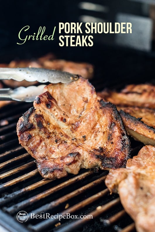 Grilled Pork Steak Recipe BBQ Pork Shoulder Steaks on a grill with a tong 