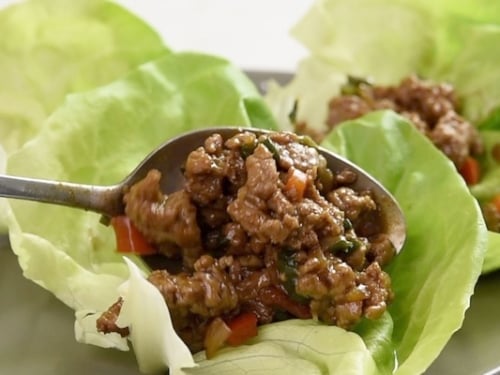 Spooning the cooked ground turkey into a lettuce cup