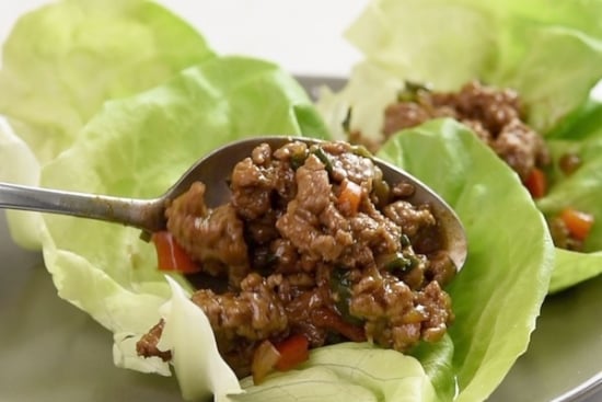 Spooning the cooked ground turkey into a lettuce cup