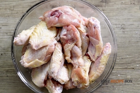 Raw chicken wings seasoned with salt & pepper in a bowl