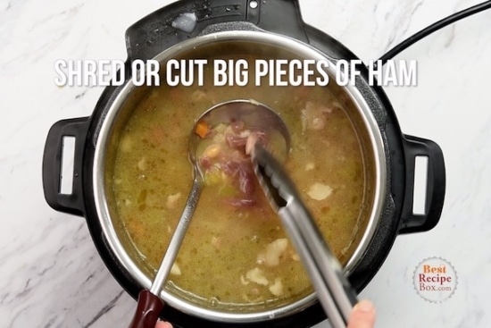 Using tongs to shred ham pieces