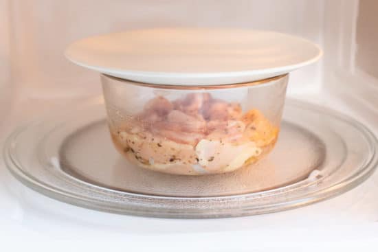 Lid on bowl with chicken in microwave
