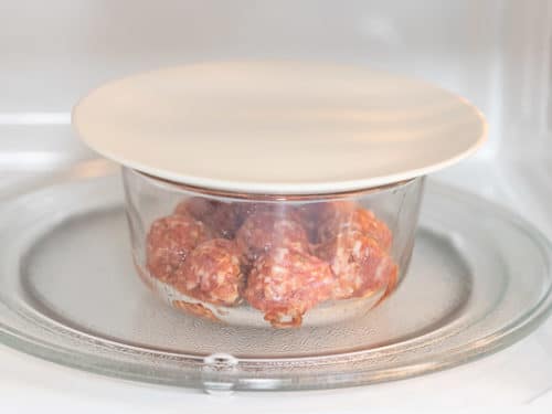 Lid covering bowl of meatballs in microwave