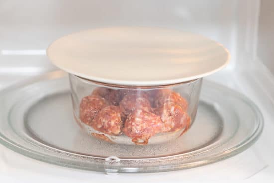 Lid covering bowl of meatballs in microwave