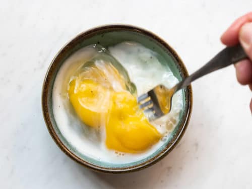 Eggs and milk beaten together with a fork in a microwave safe bowl