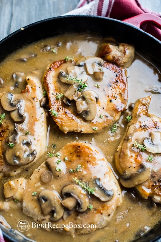 Smothered pork chops recipe with mushroom gravy in a cast iron skillet 