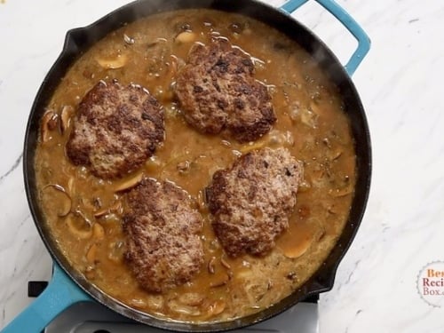 Cooked patties added to mushroom gravy in the skillet