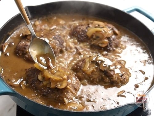 Pouring gravy over the top of the beef patties