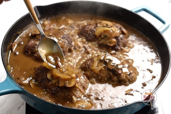 Pouring gravy over the top of the beef patties