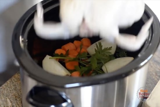 Placing chicken in slow cooker over vegetables