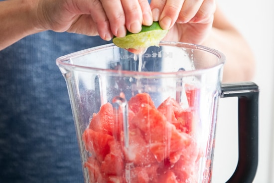 Squeezing lime into blender with watermelon cubes