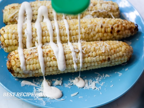 Drizzling ranch dressing over corn