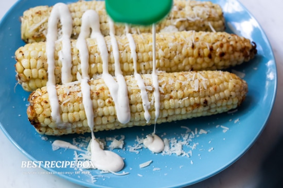 Drizzling ranch dressing over corn
