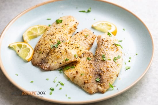 White fish fillets with lemon pepper on a plate