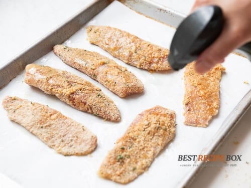 Spraying fish fillets with oil