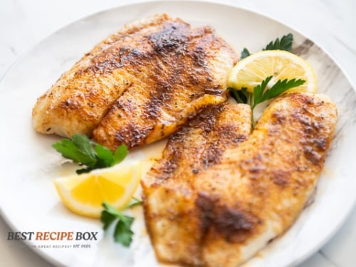 air fried cajun white fish on a plate with lemon wedges