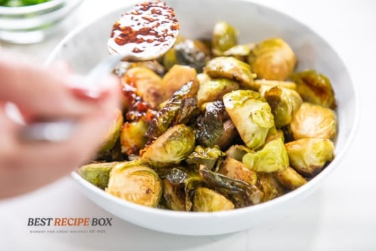 adding spoonful of chili crisp over the brussels