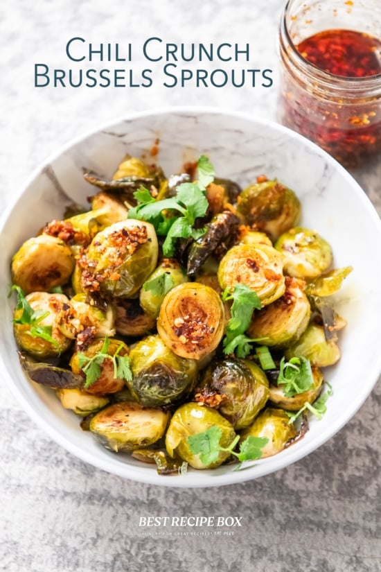 bottle of chili crisp next to bowl of brussels sprouts 