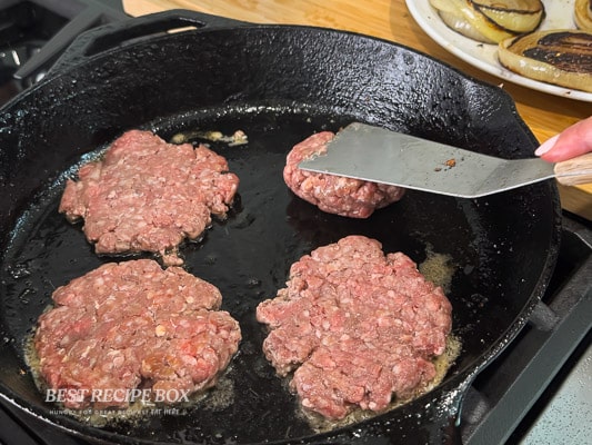 pressing beef patties on skillet
