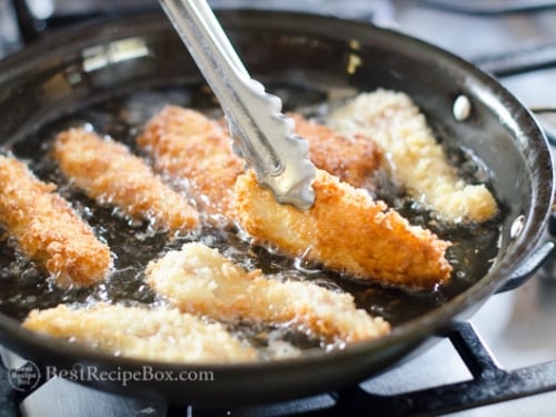 Turning the chicken strip in the pan with tongs