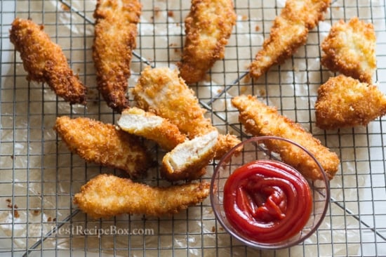 Chicken tenders on a cooling rack with ketchup in a bowl