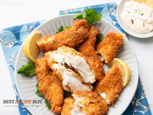 cooked crispy fried fish fillets on plate with dip