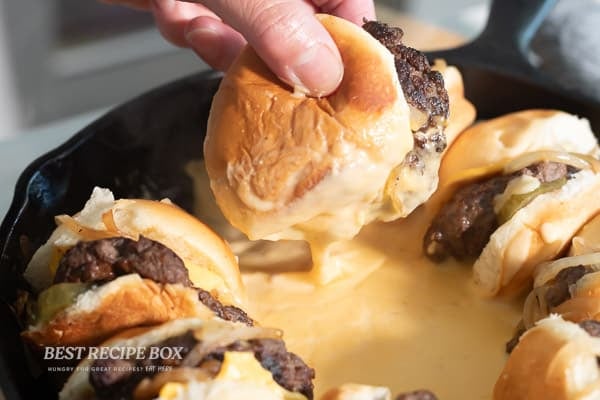 holding cheesy slider in sauce