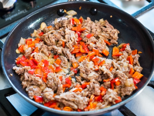 Sausage, onion and bell peppers cooked in a skillet