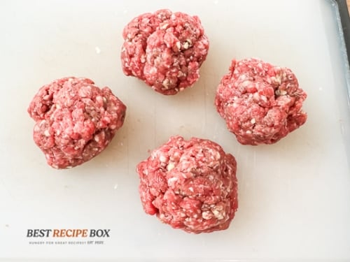 four burger ball patties on board