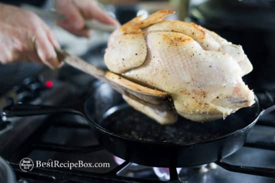Whole chicken in cast iron skillet on stove top