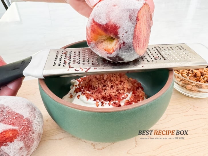 shaving frozen peaches over the cream mix