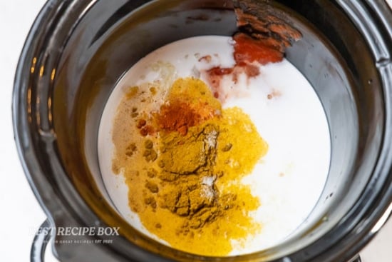 spices and coconut milk in slow cooker pot
