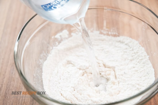 Pouring water into the flour mix for the batter